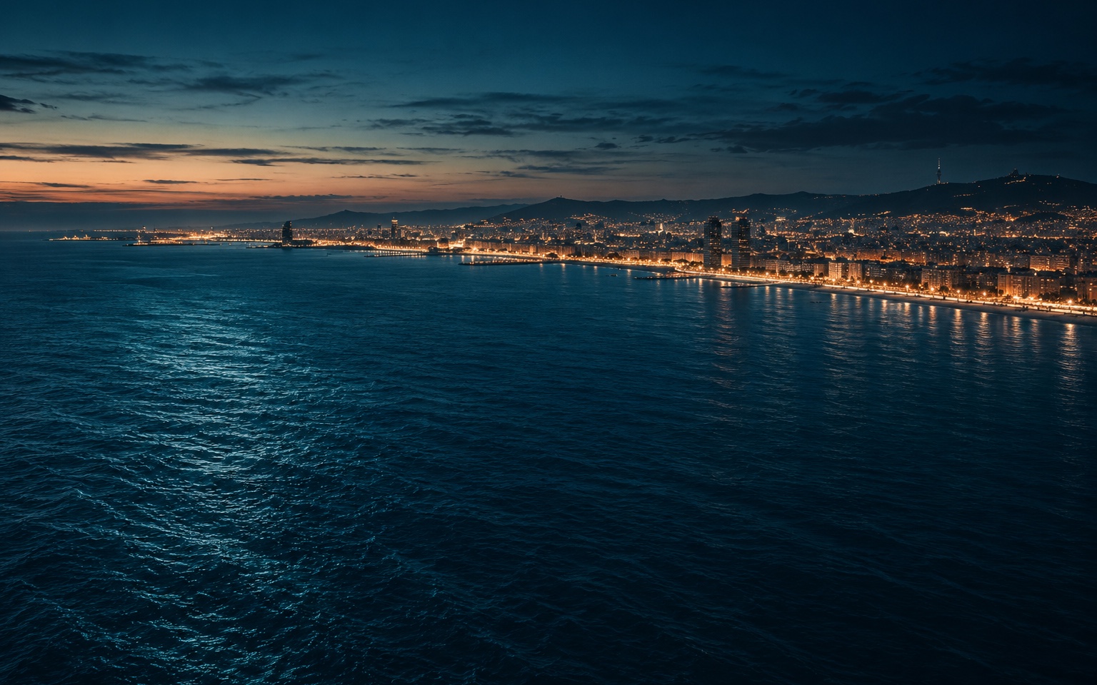 The Barcelona coastline at blue hour, seen from out over the Mediterranean